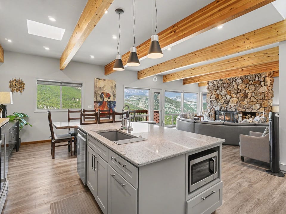 Sunlight streams through skylights onto rustic wood beams, framing your open-concept kitchen, dining, and living space. Enjoy mountain views from every window!