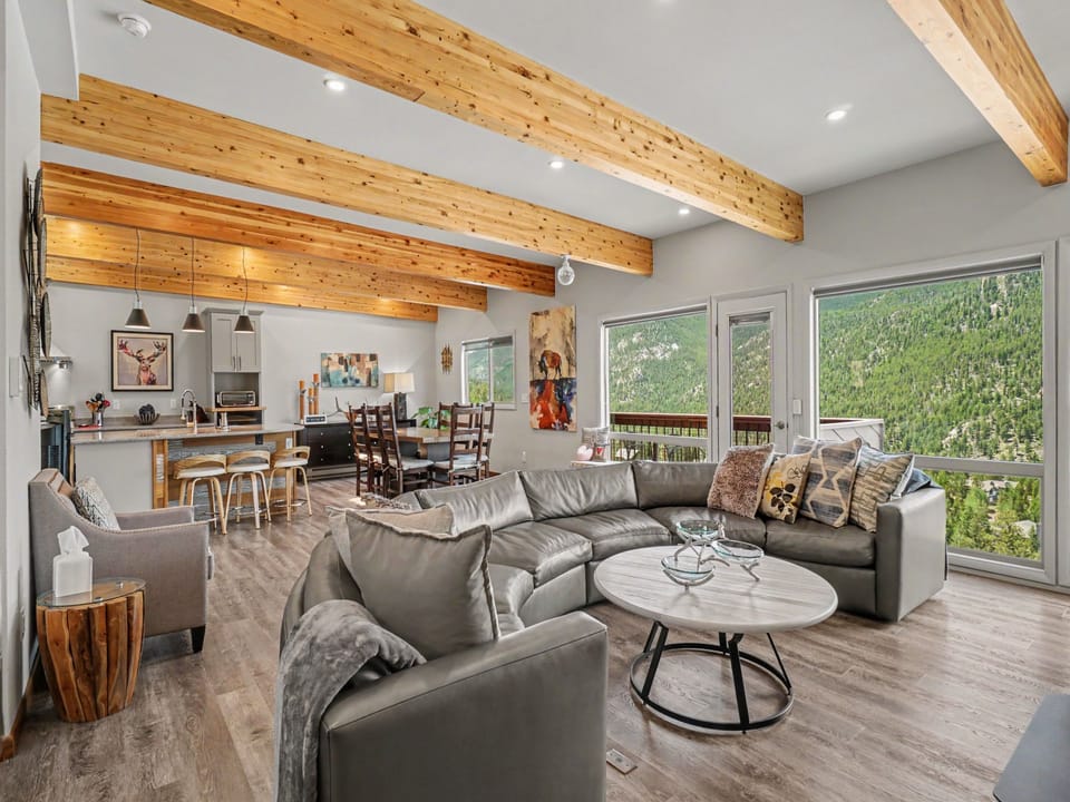 Relax in your open-concept living space with vaulted ceilings, exposed beams, and stunning mountain views. The bright, modern layout seamlessly connects living, dining, and kitchen areas—perfect for gathering after a day of adventure.