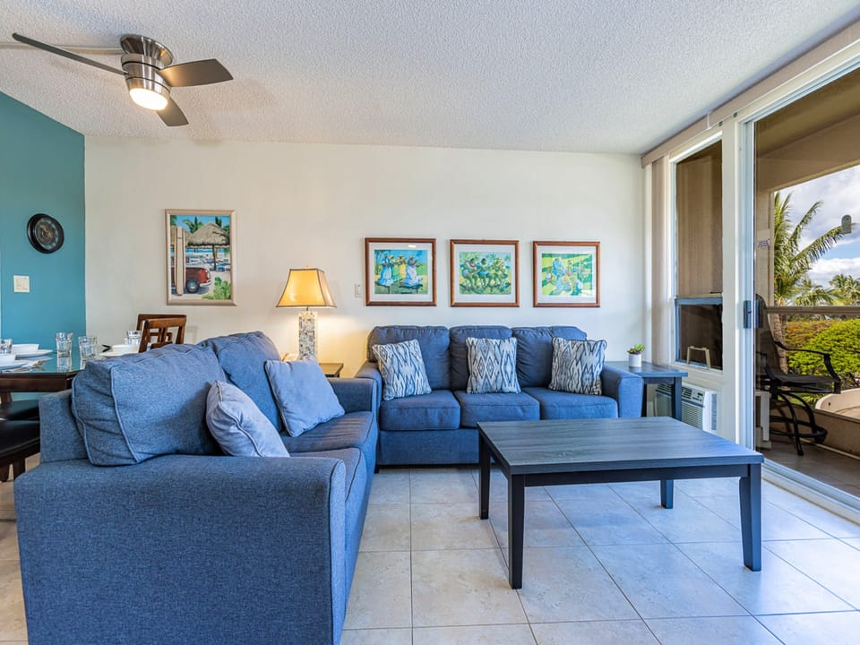 Unwind in your spacious living area with plush blue sofas, tropical art, and a private lanai.