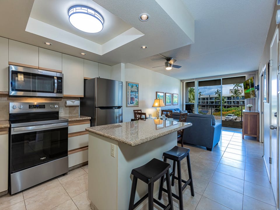 Your bright, open-concept space flows seamlessly from the kitchen with stainless steel appliances to the inviting living area with tropical views beyond.