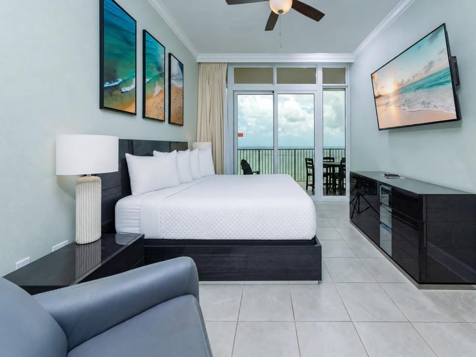 Plush king bed in the master suite invites rest while the coast view stretches beyond your balcony doors