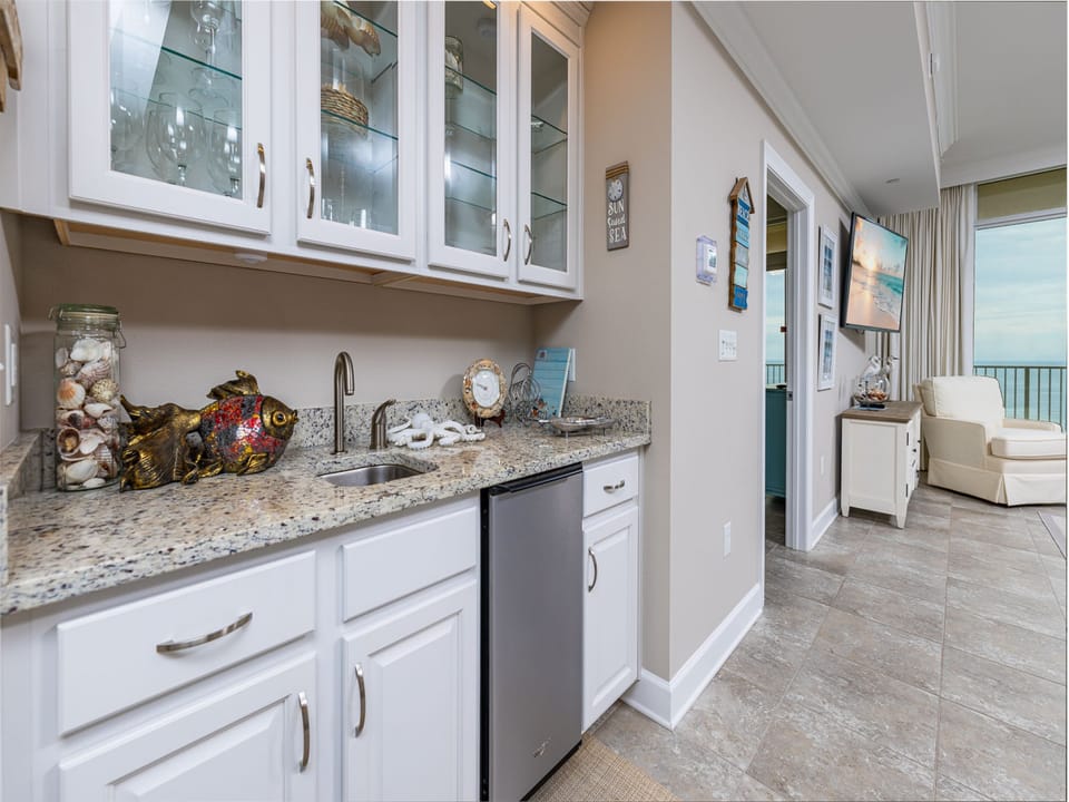 A wet bar offers a cool sip as you unwind and listen to waves beyond the living room's cozy chair