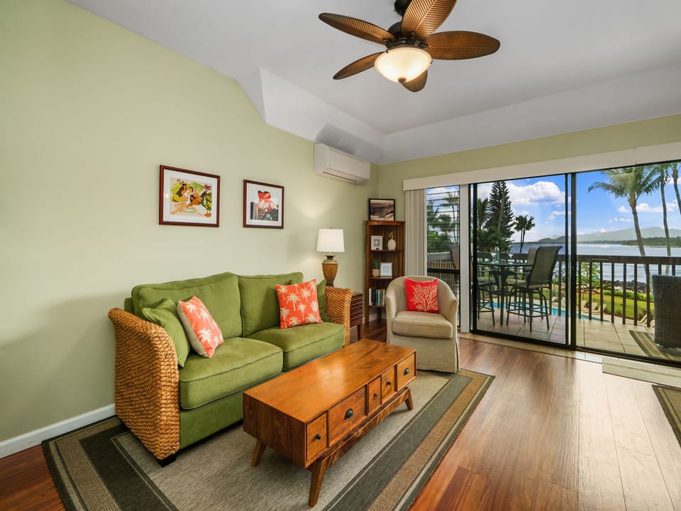 Tropical-inspired living room with plush seating and cooling ceiling fan, while savoring breathtaking water views from your private lanai overlooking swaying palms.
