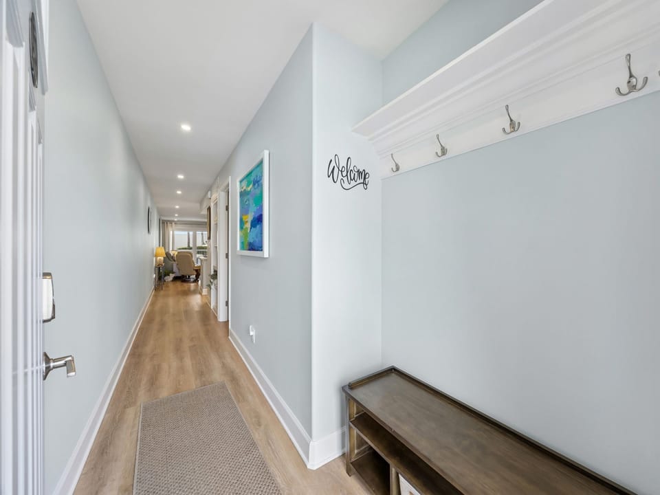 Step into your private hallway with soft blue walls, warm wood floors, and a welcoming entryway bench with convenient hooks for your belongings.