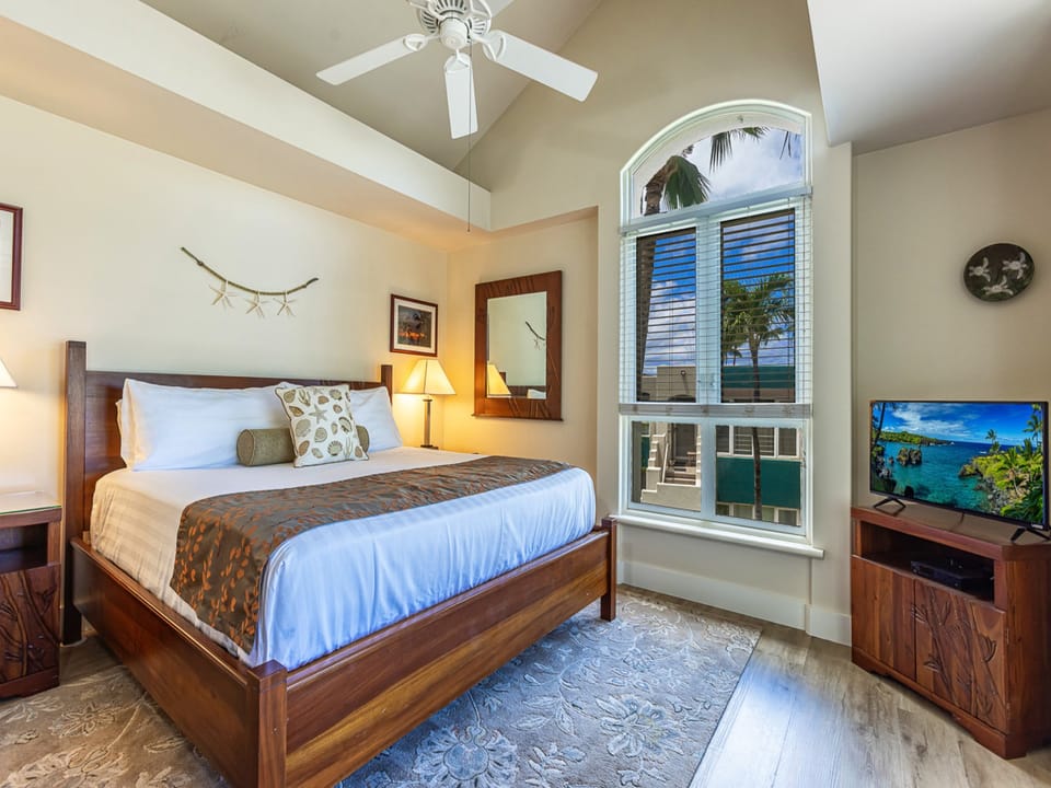Your tropical bedroom retreat features crisp linens, coastal charm, and a stunning ocean view. Unwind beneath the ceiling fan, relax on your cozy bed, and wake up to paradise right outside your window.