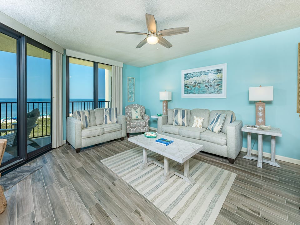 Bright sunlight fills the living room as you relax on soft couches with a soothing coastal view nearby