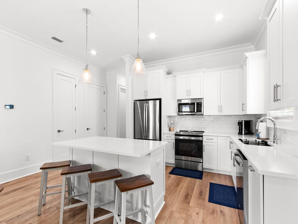 Bright pendant lights glow above the breakfast bar where you gather for casual meals and lively conversation