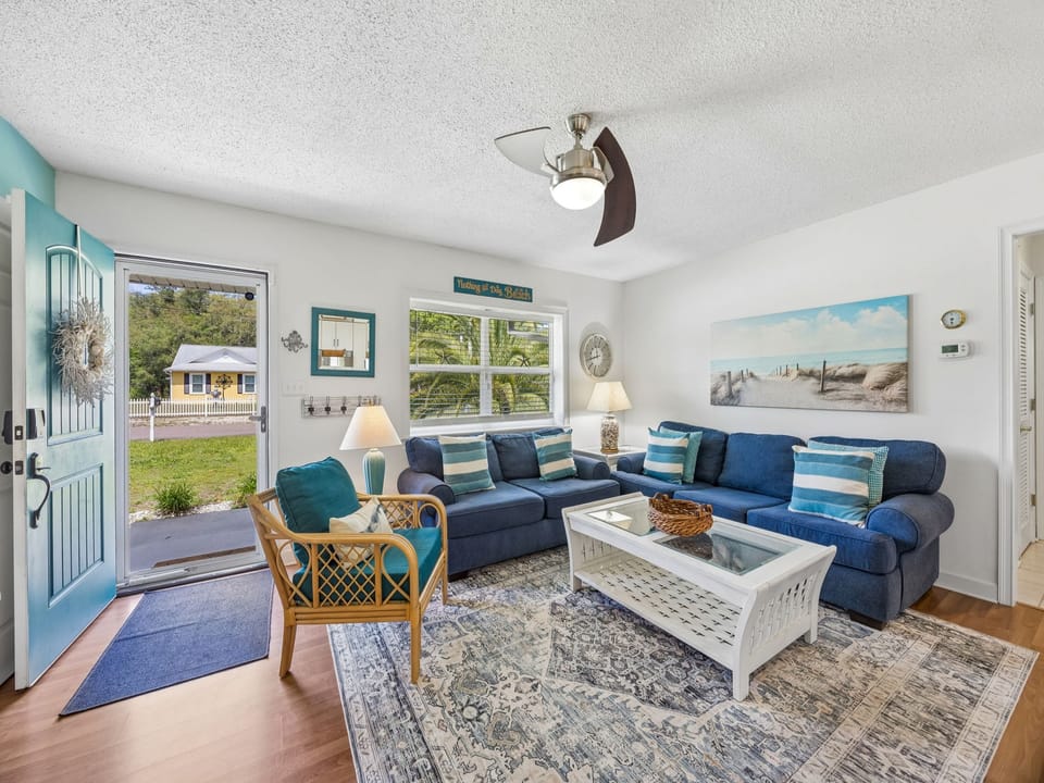 Sink into the plush navy sofas and unwind in your coastal-inspired living room, where beach hues and sunny windows create your perfect retreat.