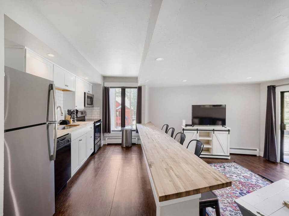 Gather around this expansive communal table where your group can share meals, plan adventures, or simply enjoy each other's company in this bright, open-concept space.