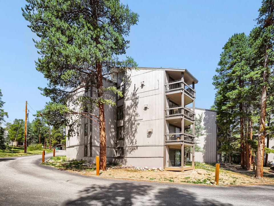 Modern multi-level vacation property nestled among tall pines, featuring private balconies and convenient street access in a peaceful forested setting.