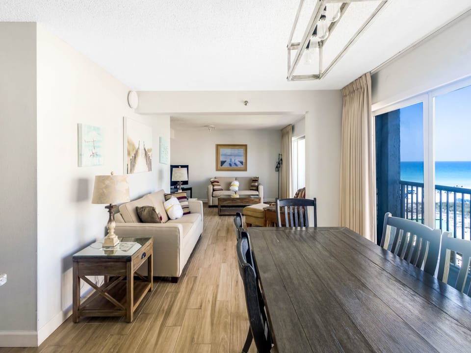 Step into your bright, open living space where comfort meets coastal charm. Sink into the plush sofa, gather around the spacious dining table, and let your eyes drift to the sparkling ocean just beyond your private balcony.
