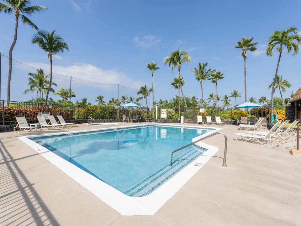 Dive into your tropical escape at this sparkling pool, framed by swaying palms and sunny skies—your perfect Hawaiian retreat awaits.