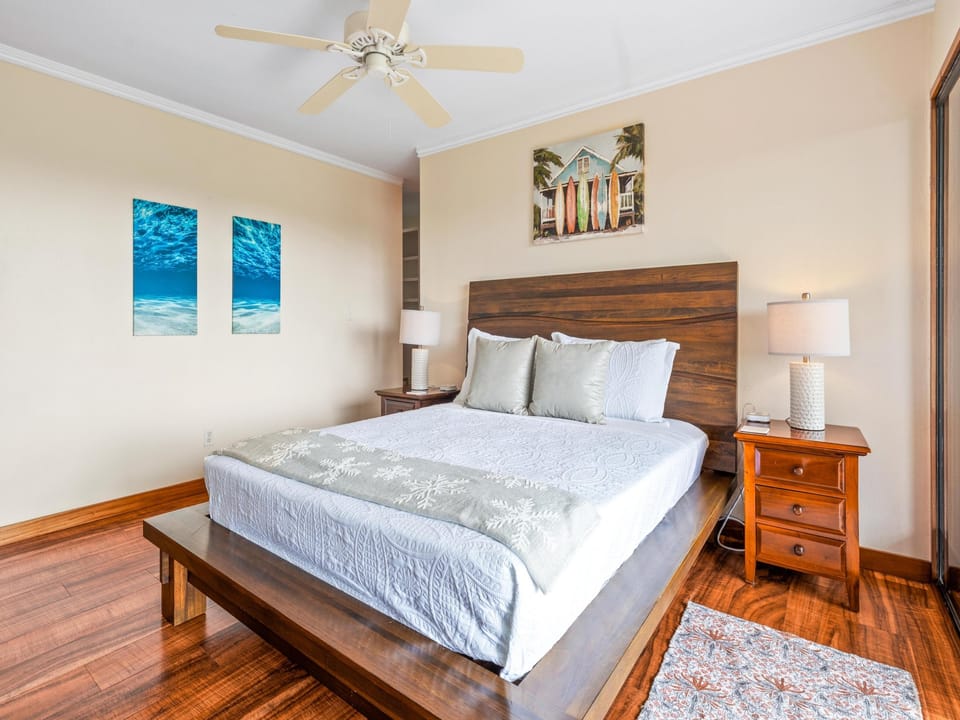Sink into crisp linens in your bedroom, where coastal art sets a relaxed tone and warm wood finishes add natural charm. The ceiling fan keeps you comfortable all night long.