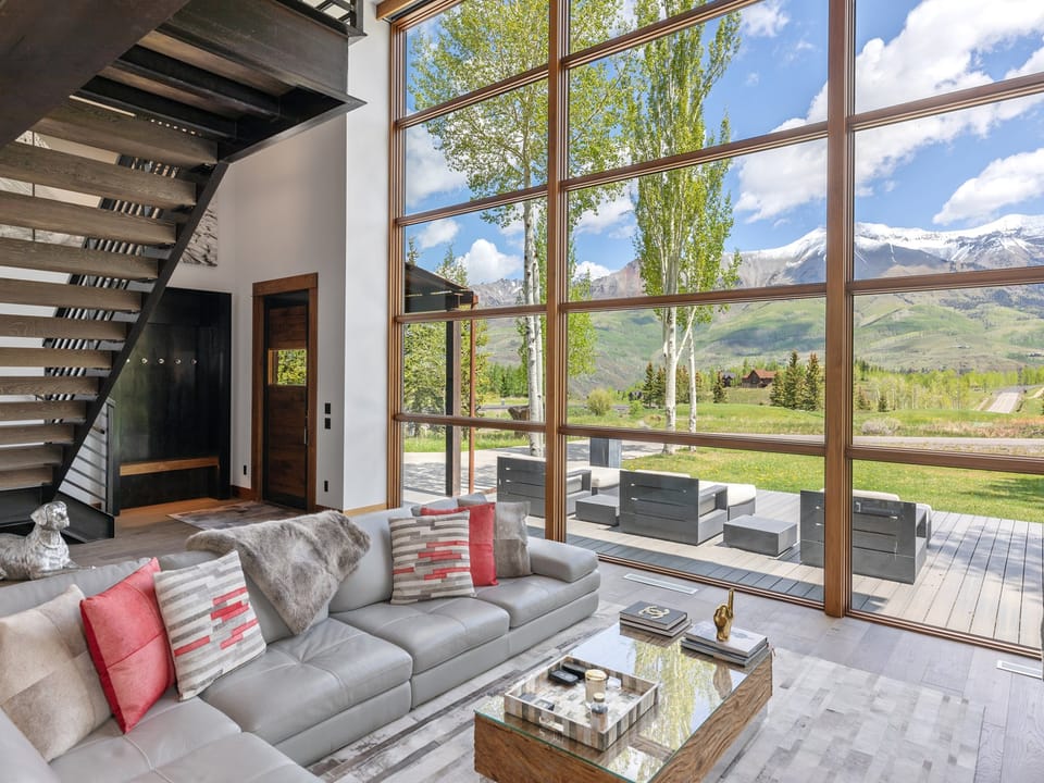 Sink into luxury as floor-to-ceiling windows frame breathtaking mountain panoramas from your elegant living space. Natural light floods the open-concept room, where contemporary design meets alpine serenity just steps from your private deck.
