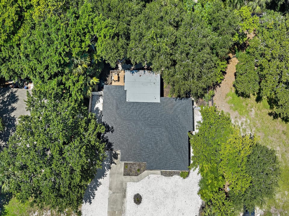 Aerial view of the property nestled among lush trees, offering a secluded retreat with natural surroundings and easy access to scenic walking paths.