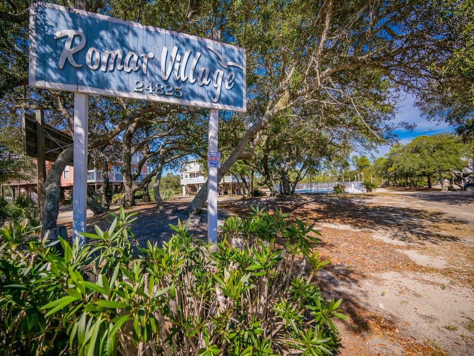 Welcome to Romar Village, where lush greenery and a charming sign greet you as you approach your perfect getaway