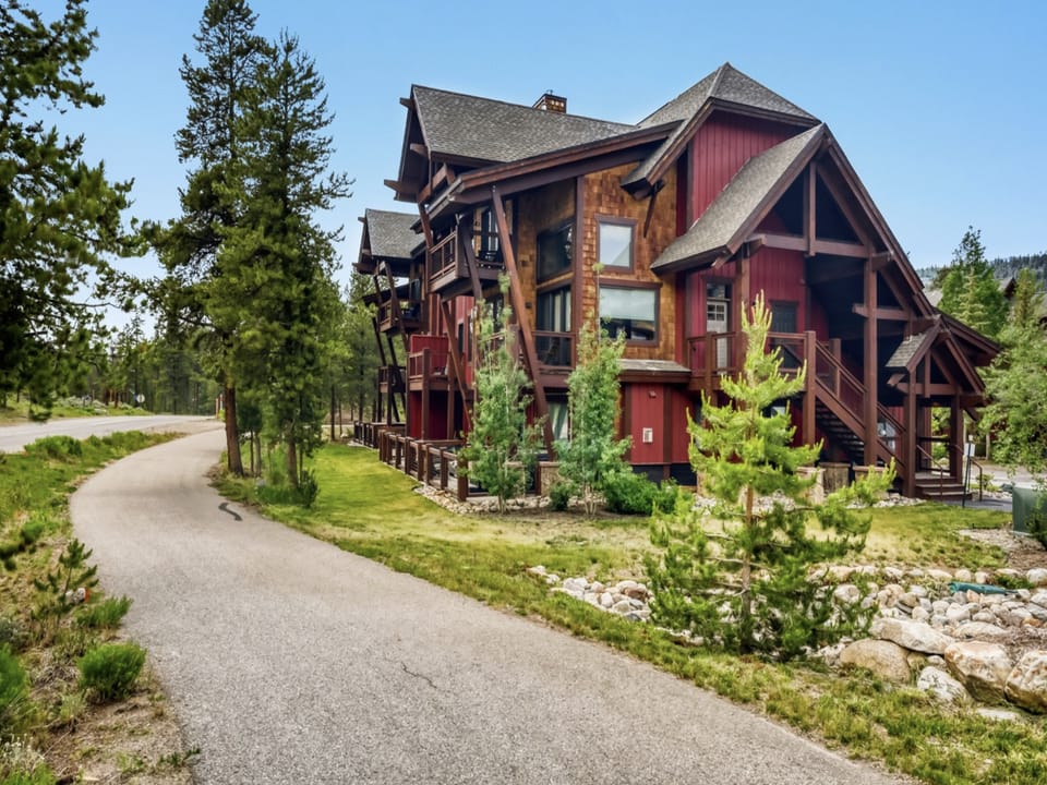 Stunning mountain architecture nestled among evergreens, with distinctive timber framing and rich red siding that blends beautifully with the natural surroundings.