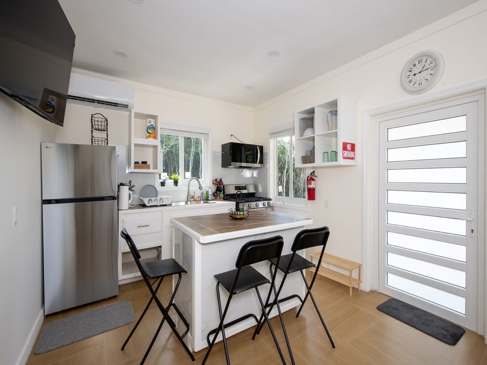 Modern island kitchen is equipped with a refrigerator, gas range and oven, and a microwave.