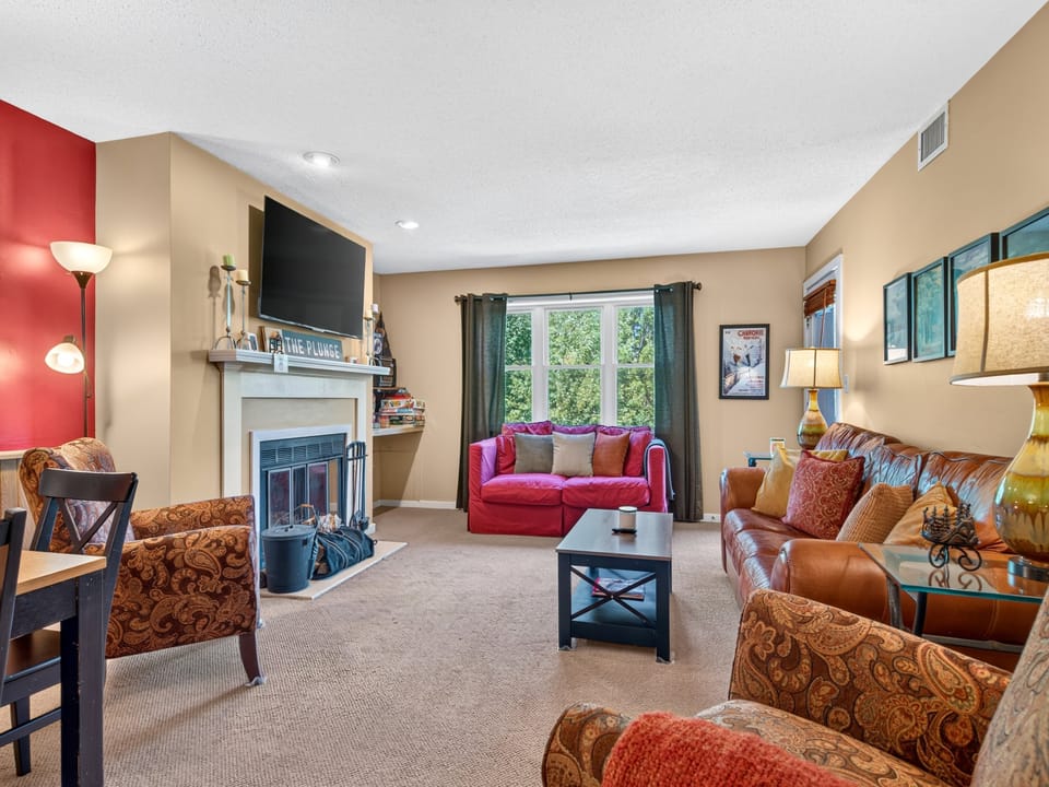 Settle into this spacious living room where plush seating and a cozy fireplace invite you to unwind. Natural light streams through large windows, creating a warm gathering space for your group.