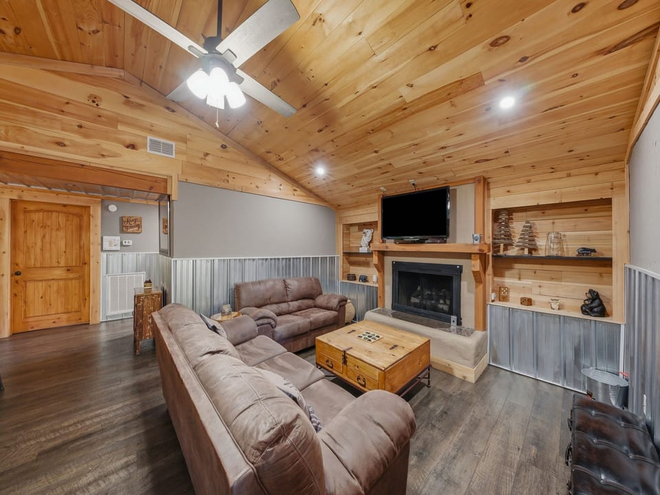 Sink into plush sofas under soaring wood-planked ceilings while your fireplace crackles nearby—this cozy living space blends rustic charm with modern comfort, perfect for unwinding after a day of exploring.