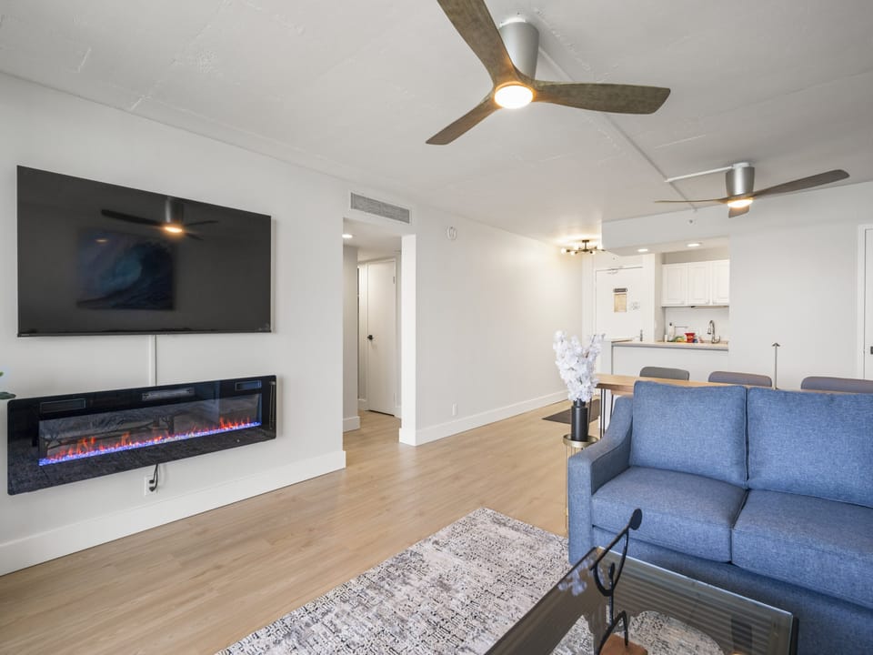 Unwind in your spacious open-concept living area, where modern comfort meets coastal style. Relax by the electric fireplace, enjoy meals at the dining table, or prepare snacks in your bright kitchenette—all under stylish ceiling fans.