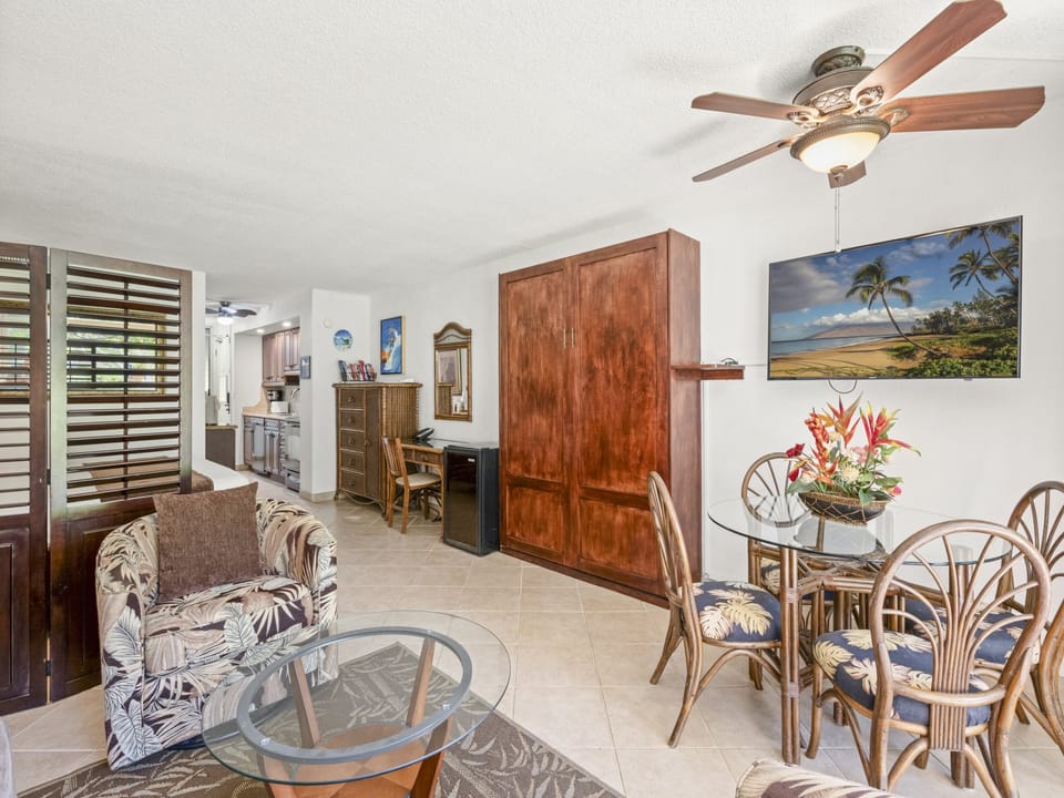 Relax in your tropical-inspired living and dining space featuring open layout, ceiling fans for comfort, island décor, and convenient access to the kitchen—perfect for unwinding after beach adventures.