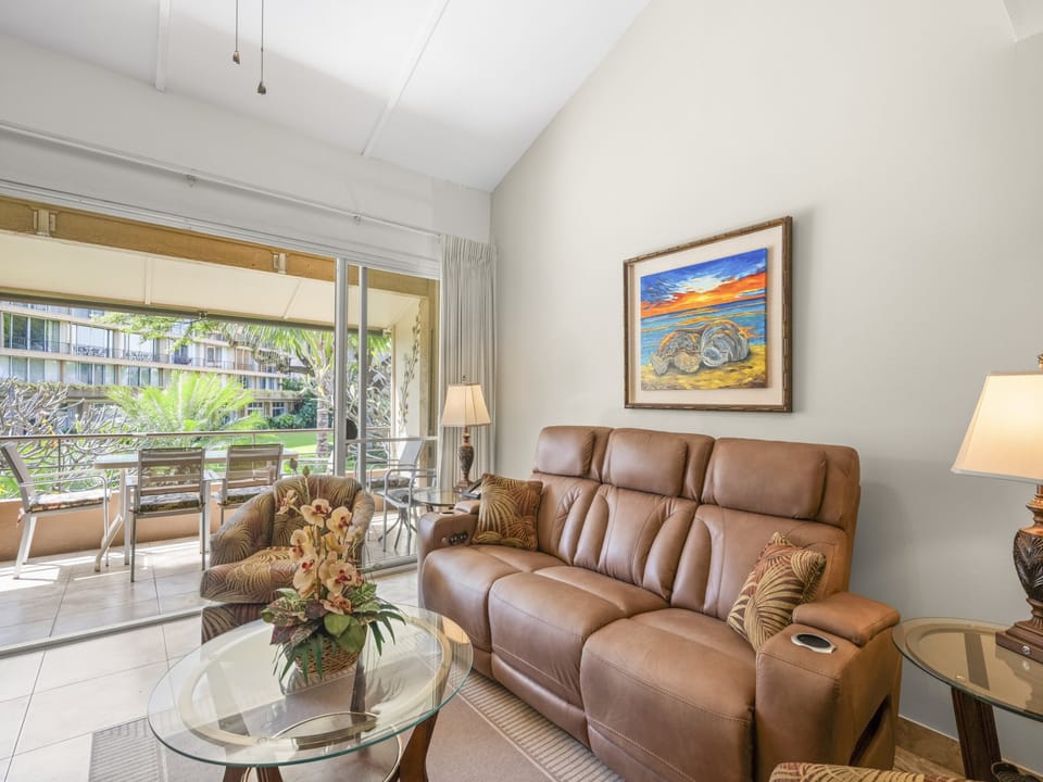 Unwind in your spacious living room, where coastal artwork and comfortable seating invite you to relax after a day of island adventures, with garden views just beyond your balcony.