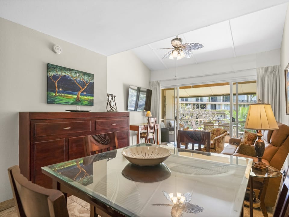 Gather around this inviting dining space, where a glass table reflects tropical decor and natural light streams through the balcony doors, creating a warm setting for your vacation meals together.