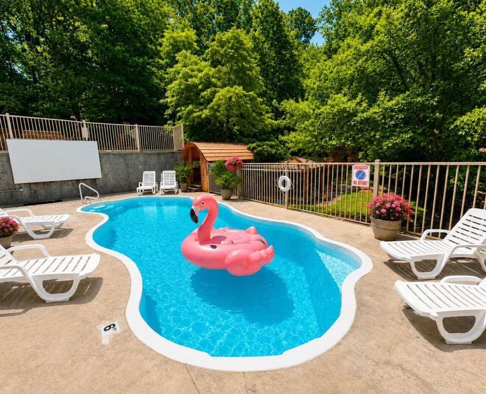 Private resort-style pool with outdoor movie screen, lounge seating, and peaceful wooded views — the perfect luxury getaway for families and group vacations.