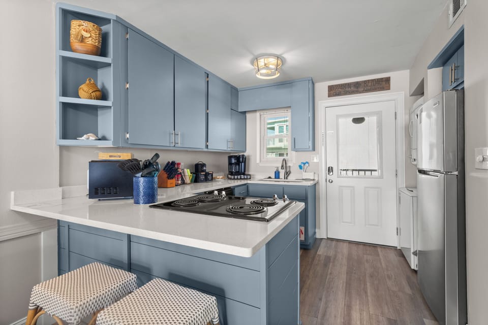 Chic blue kitchen with breakfast bar, coffee nook, and stainless fridge