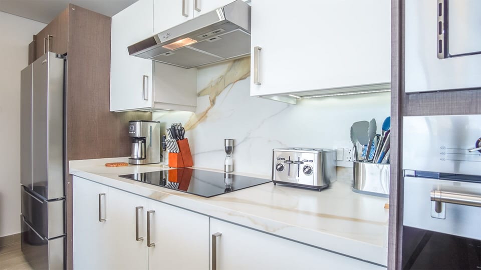 Close in on the stove top, with detail of the cabinets microwave, and double door refrigerator beyond. Lots of storage as well in this fully equipped kitchen.