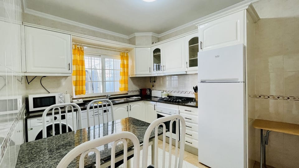 Kitchen equipped with fridge, dishwasher, washing machine, microwave, oven, toaster, coffee maker, juicer and kettle.