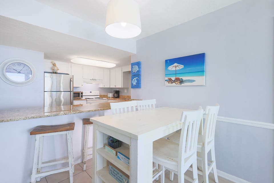 This kitchen features modern appliances, granite countertops, and a bright dining area with beach-themed decor