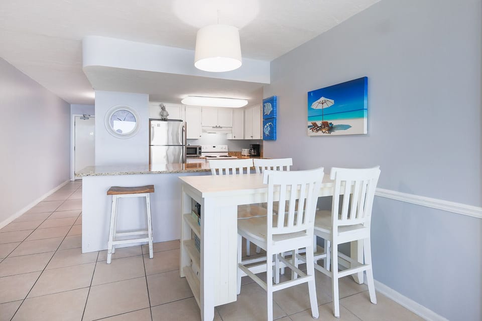 This kitchen features sleek appliances, granite countertops, and a cozy dining area with beach-themed decor