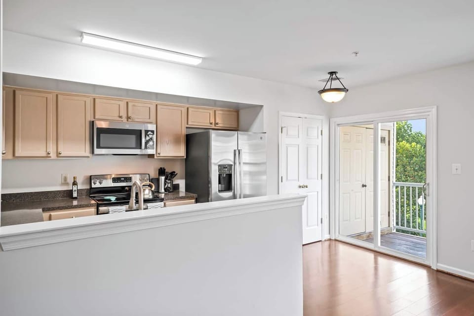 Efficient kitchen layout with beige cabinets, stainless appliances, and balcony.