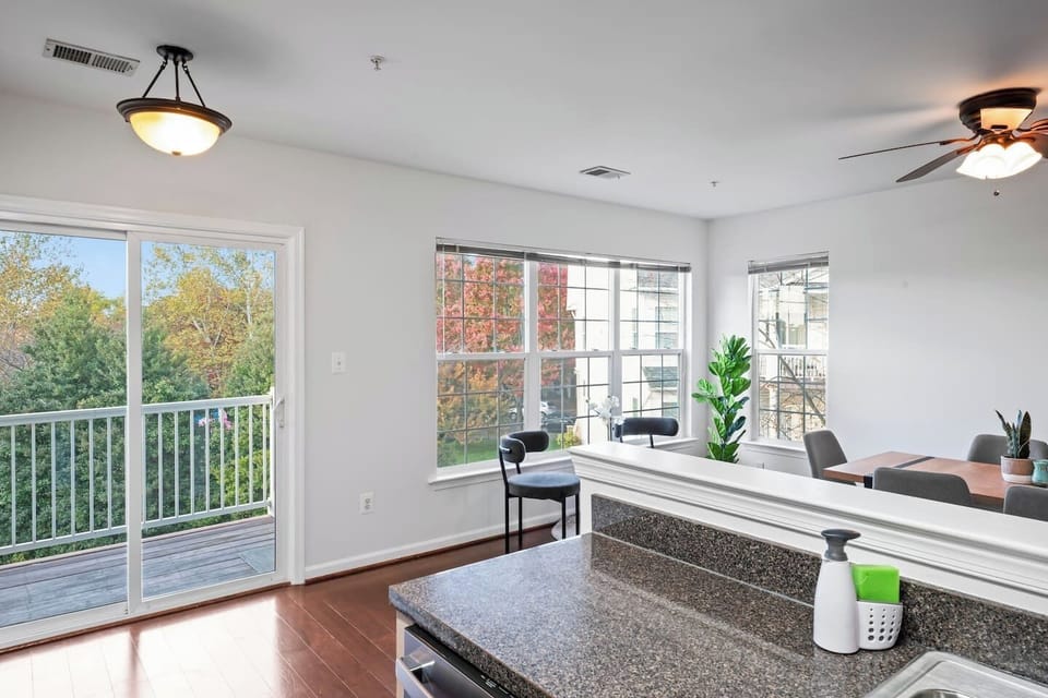 Modern kitchen with nature views, featuring granite counters, cozy dining space.