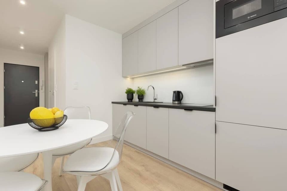 Another view of the kitchen, showcasing black countertops, white cabinets, and a fresh bowl of lemons.
