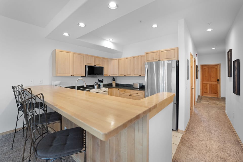 Your spacious kitchen features warm wood cabinetry, granite counters, and a breakfast bar perfect for morning coffee and casual meals.