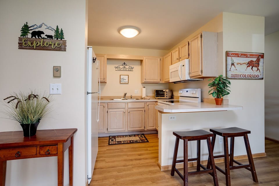 Your fully equipped kitchen awaits with warm wood cabinets, modern appliances, and a breakfast bar where you can enjoy your morning coffee.