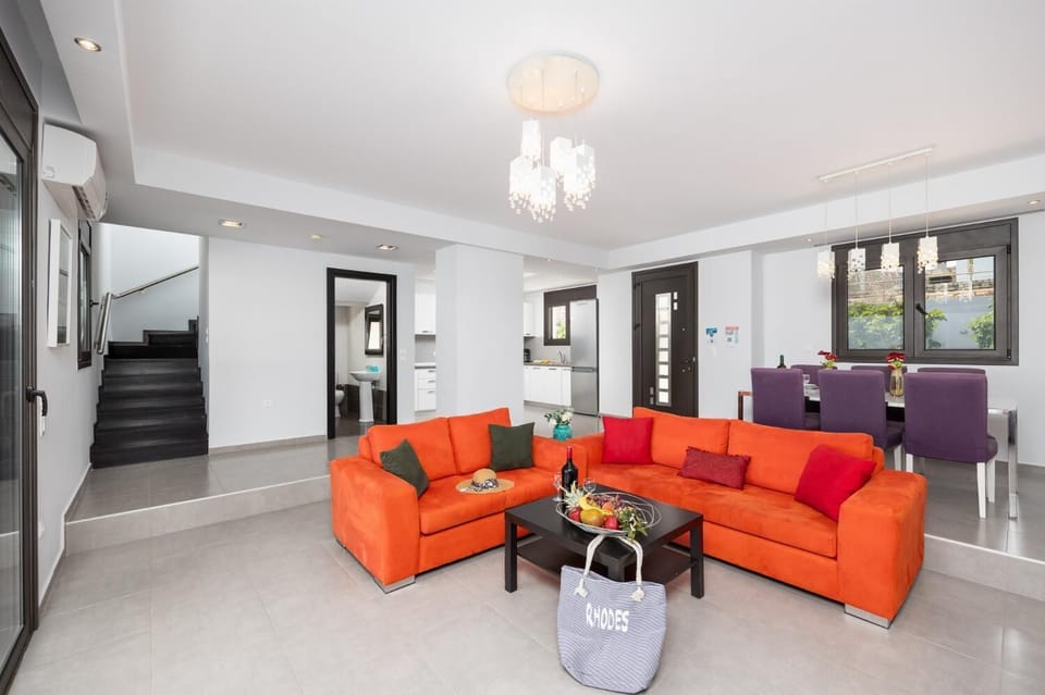 Open-plan living room with sofas, dining area, kitchen, ornamental fireplace, A/C, WiFi internet, satellite TV, and sea views