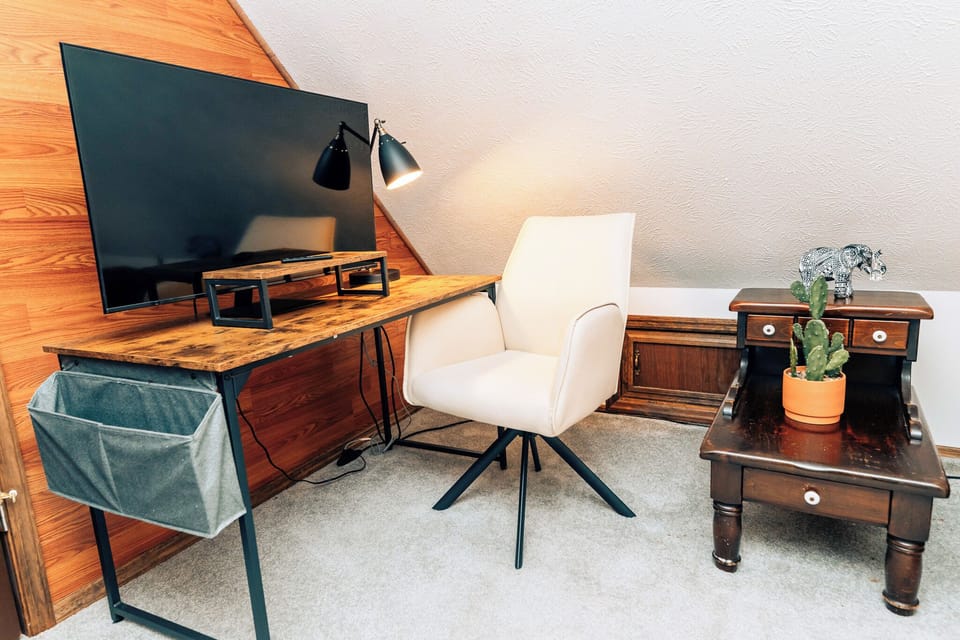 Upstairs bedroom workspace with desk, TV, and cozy chair.