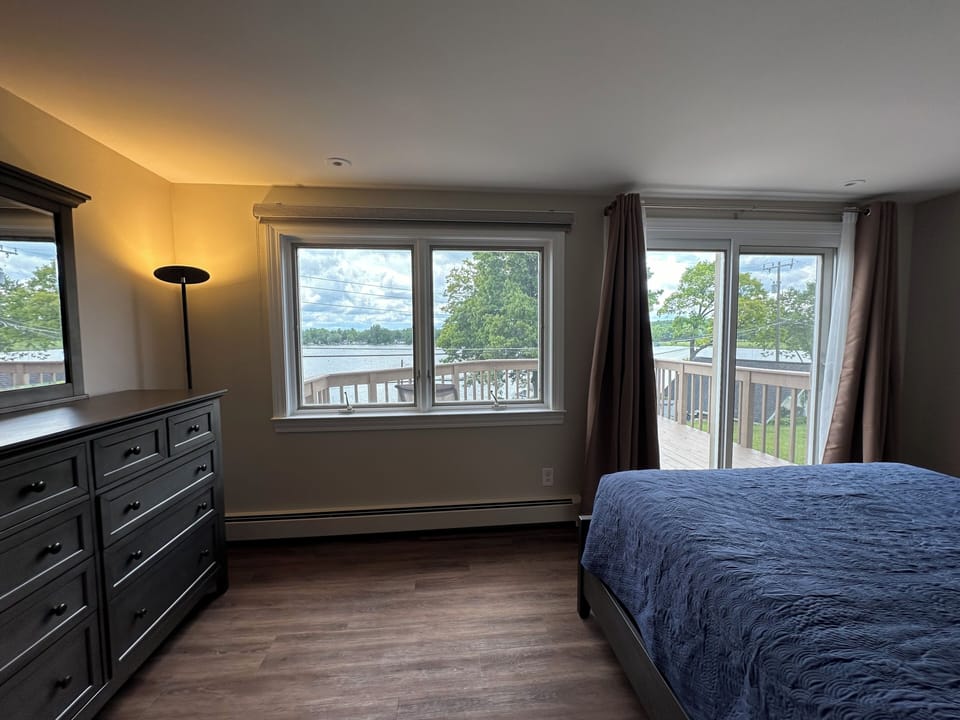 Upstairs bedroom with queen bed, lake view, and deck with loungers.