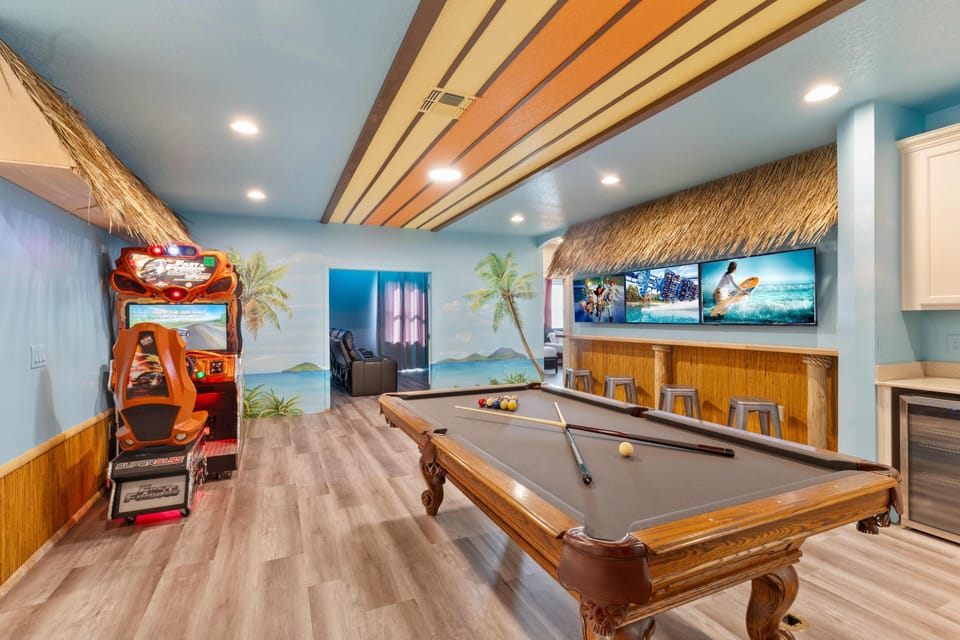 - Game room with pool table arcade racing game and tiki bar seating  
- Surfboard ceiling and tropical murals create a fun lively vibe  
- Indoor entertainment designed for families and groups