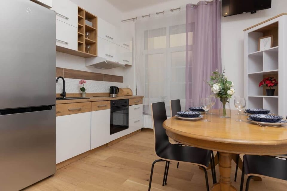 A dining area connected to the kitchen, featuring a round wooden table, black chairs, and minimalist decor.
