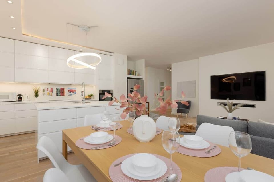A spacious dining and living area with a modern table, elegant chairs, and open kitchen space.
