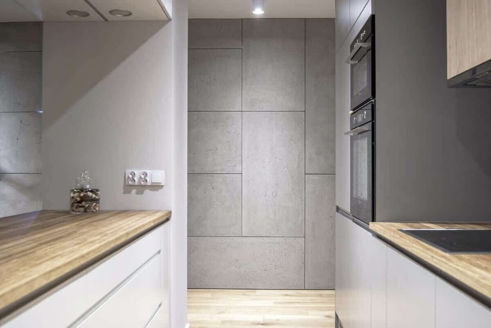 A hallway with a concrete accent wall leading to the kitchen and living space.
