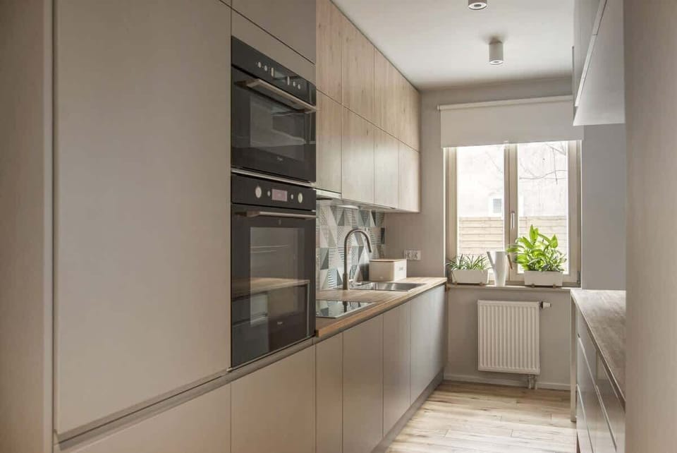 A sleek, narrow kitchen with built-in appliances, modern lighting, and a minimalist design.

