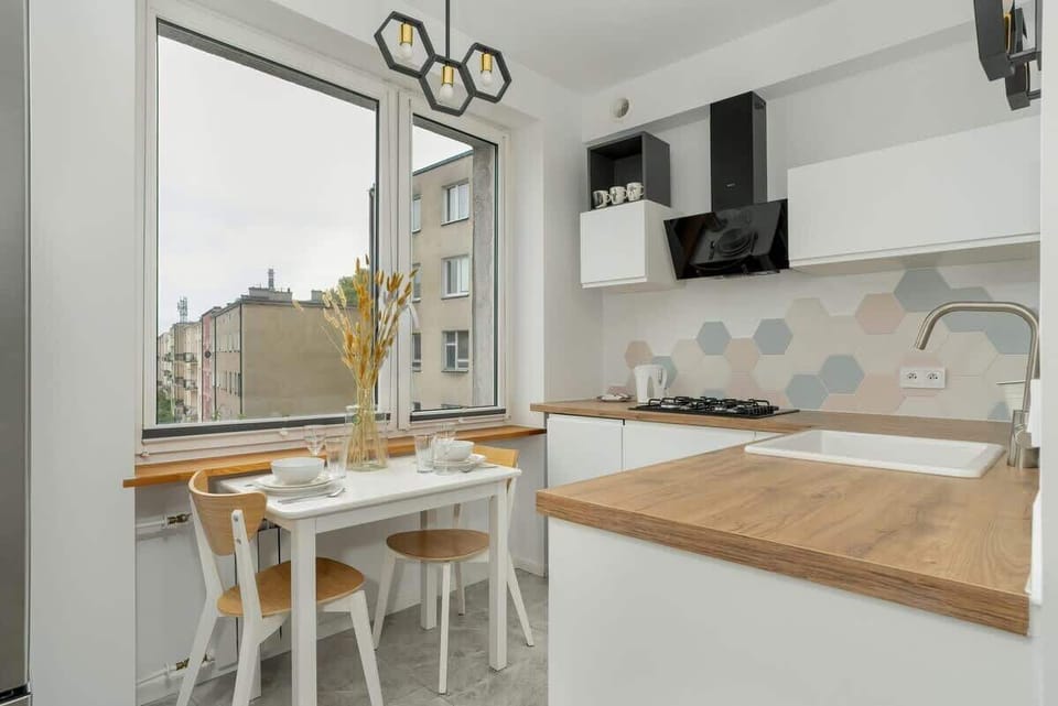 A modern kitchen with a dining area, large windows, and a minimalist black and white design.
