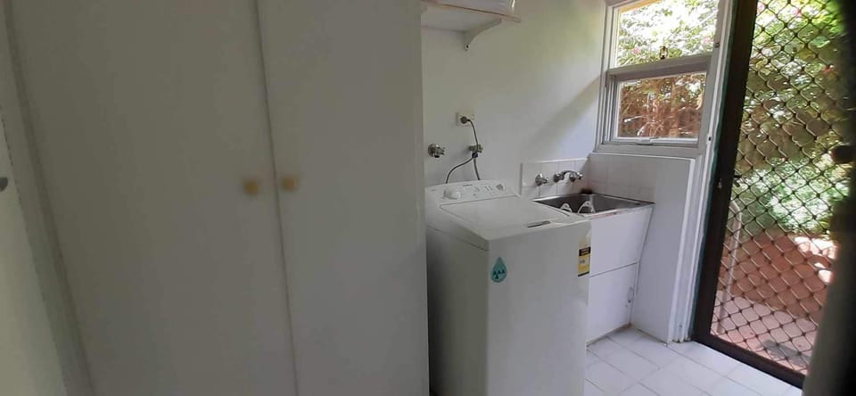 Laundry with washing machine, ironing board, broom, cleaning supplies