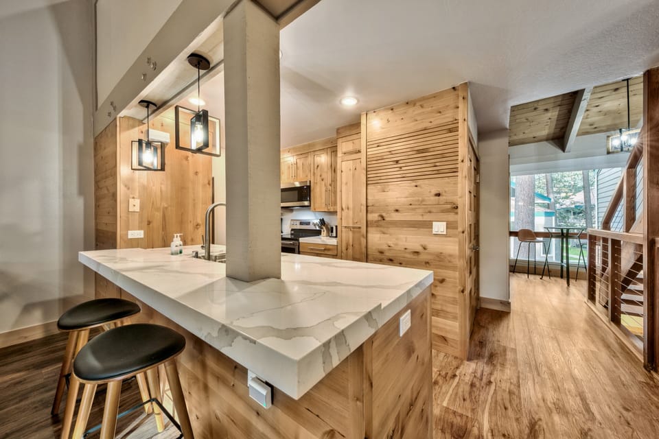 Your gourmet kitchen features warm wood cabinetry, marble countertops, and pendant lighting—perfect for preparing mountain getaway meals together.